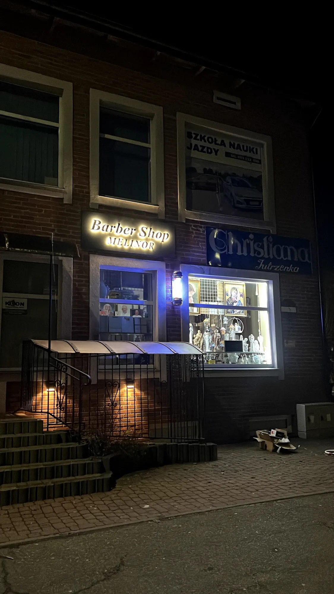 Podświetlony szyld Barber Shop Melinor przy Wyszyńskiego 9a wieczorem